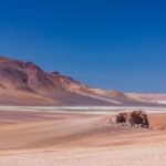 brown sand field near brown mountain under blue sky during daytime