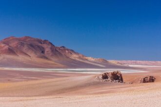 brown sand field near brown mountain under blue sky during daytime
